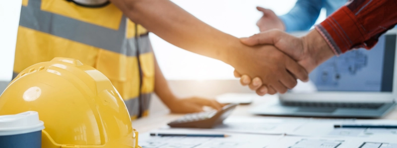 Contractor and homeowner shaking hands at construction site